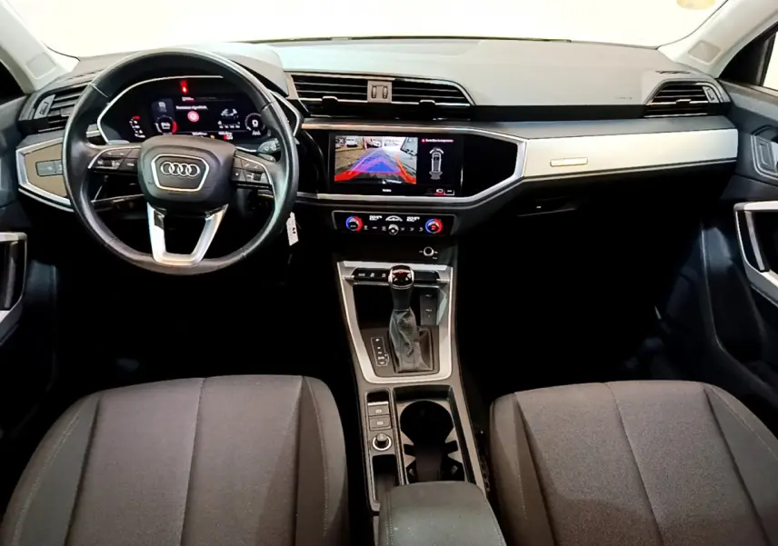 Intérieur Audi Q3 35 TDI 2021 vu de face, tableau de bord moderne avec écran tactile et volant cuir noir.