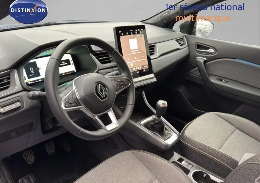 Vue intérieure côté conducteur du Renault Captur 2025, montrant le volant, la console centrale avec écran tactile et la boîte manuelle.