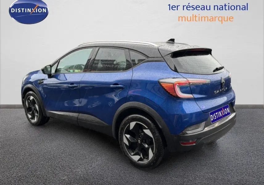 Vue 3/4 arrière droite d'un Renault Captur bleu Iron Metal avec toit noir et jantes noires distinctives.