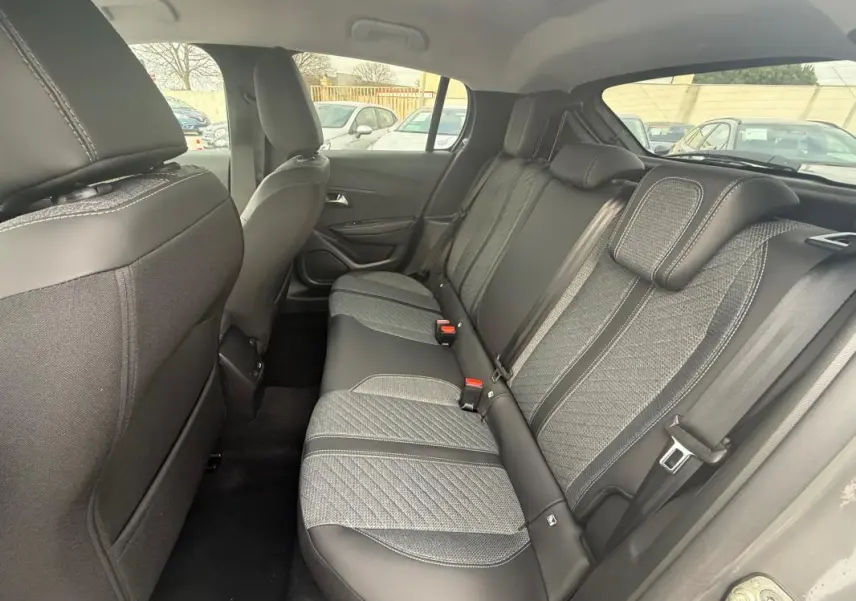 Vue intérieure arrière droite des sièges arrière gris avec sellerie mixte tissu et cuir de la Peugeot 208 Hybrid 145 Allure 2025.