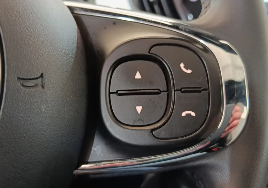 Gros plan sur les commandes du volant cuir de la FIAT 500 Hybrid blanc, boutons de gestion d’appel et navigation.