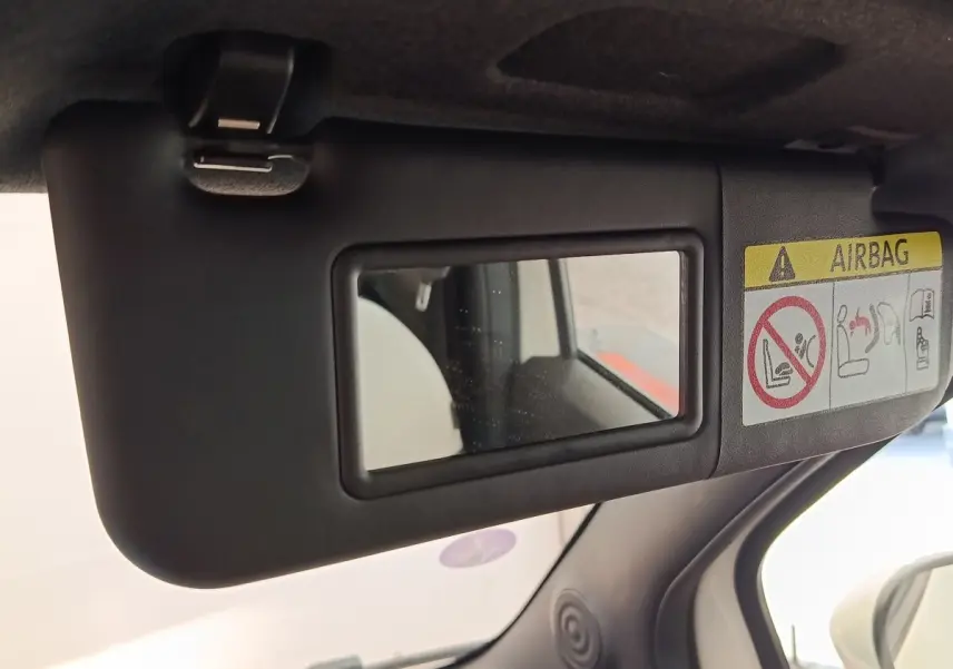 Miroir de courtoisie sur pare-soleil côté conducteur dans l’habitacle noir d’une Fiat 500 blanche.