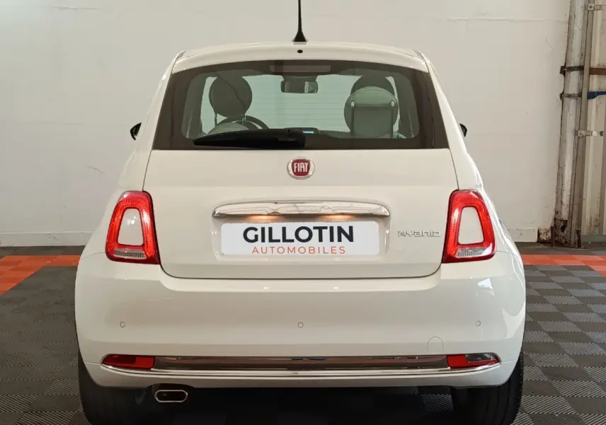 Vue arrière d'une FIAT 500 Hybrid blanche, avec feux arrière allumés et logo FIAT visible sur un sol à damier.