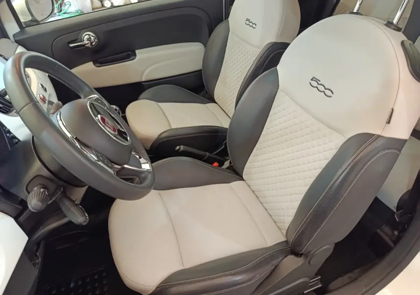 Vue intérieure côté conducteur de la Fiat 500 Dolcevita 2022 avec sièges bi-ton beige et gris et volant cuir multifonctions.
