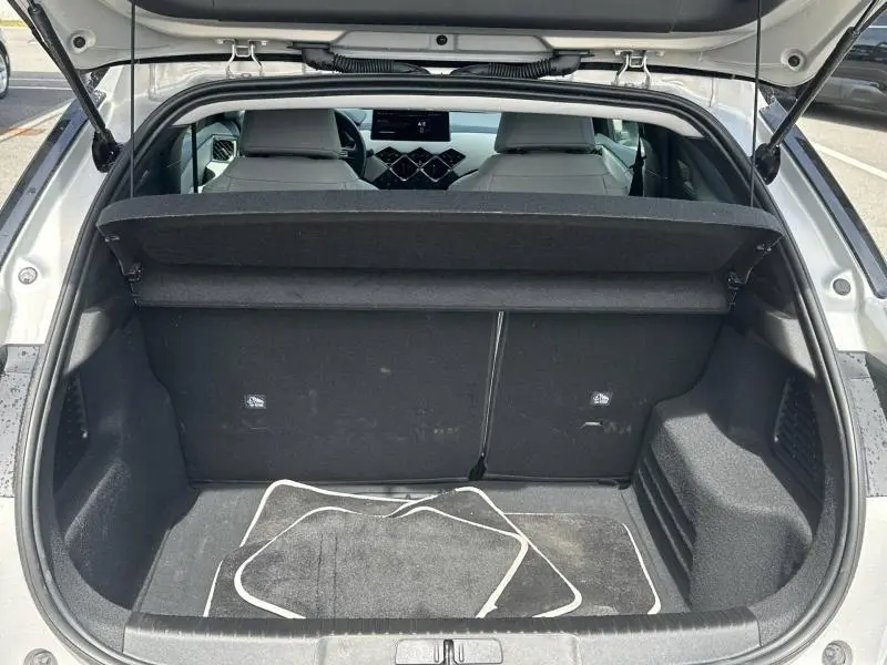 Vue arrière du coffre ouvert de la DS3 2024 Cristal Pearl avec intérieur noir et tapis de sol visibles.