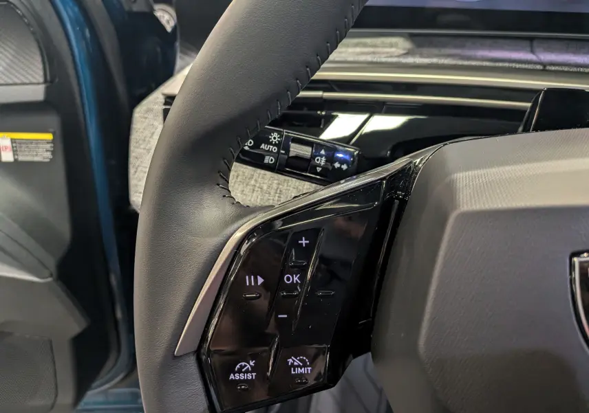 Gros plan sur les commandes au volant côté gauche du Peugeot 3008 Hybrid 145 CH e-DCS6 Allure Bleu Obsession, intérieur moderne.