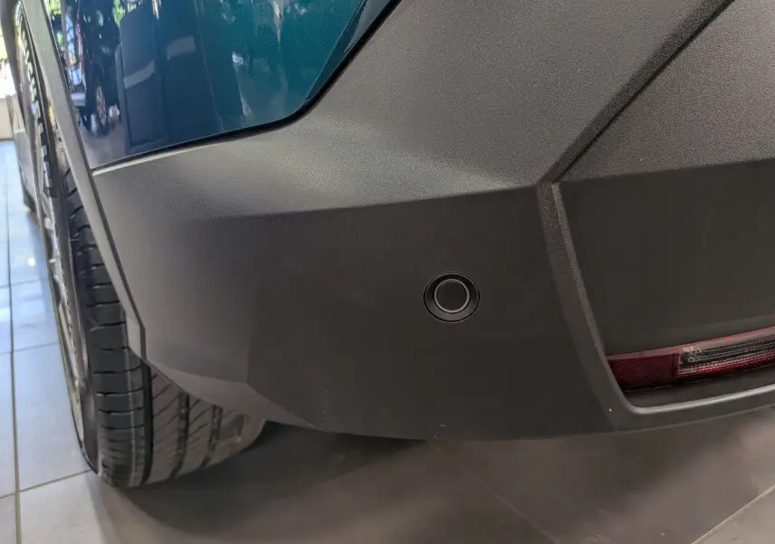 Gros plan sur le pare-chocs arrière droit bleu Obsession du Peugeot 3008 Hybrid 145 ch avec capteur de recul intégré.