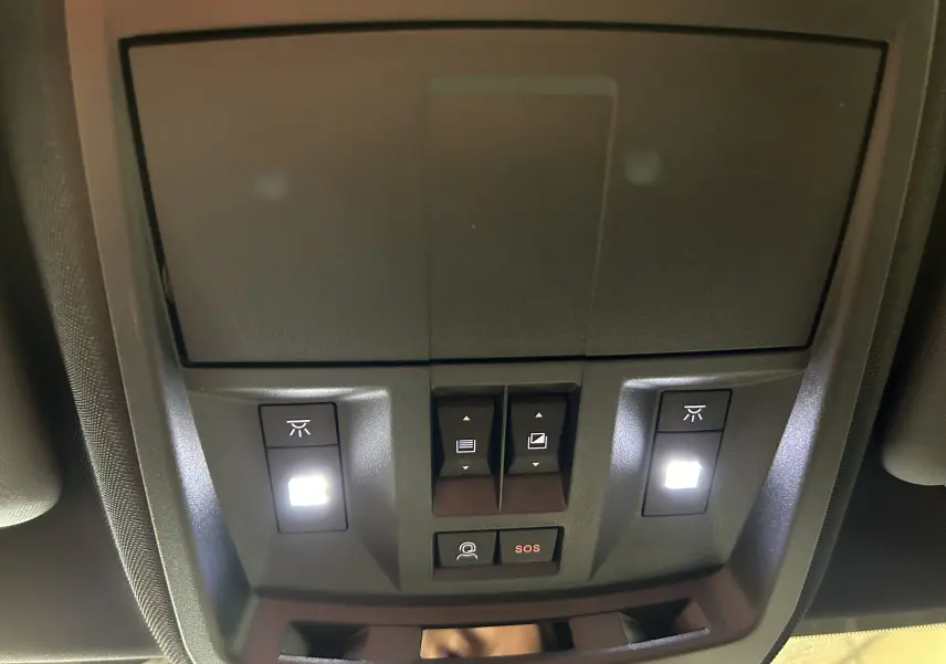 Vue en gros plan du plafonnier intérieur du Peugeot 3008 blanc, avec boutons d’éclairage et alerte SOS éclairés.