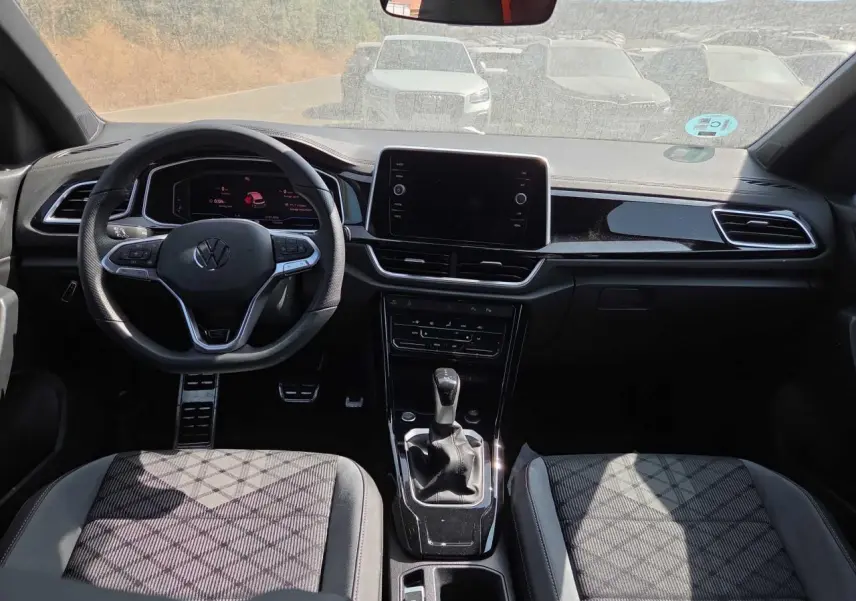 Vue intérieure avant du Volkswagen T-Roc 2025 noir métal, avec tableau de bord digital et volant multifonction R-Line.