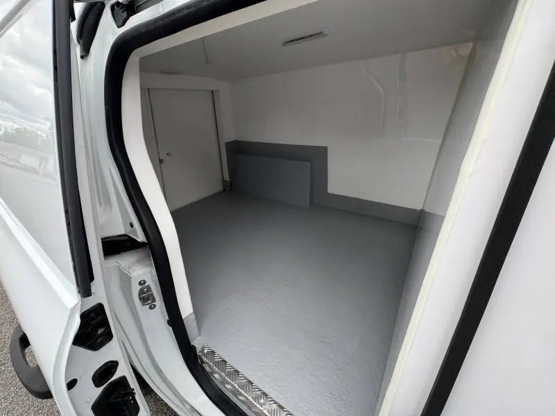 Vue intérieure de la caisse isotherme blanche du Renault Kangoo Van L2, avec porte latérale ouverte côté droit.