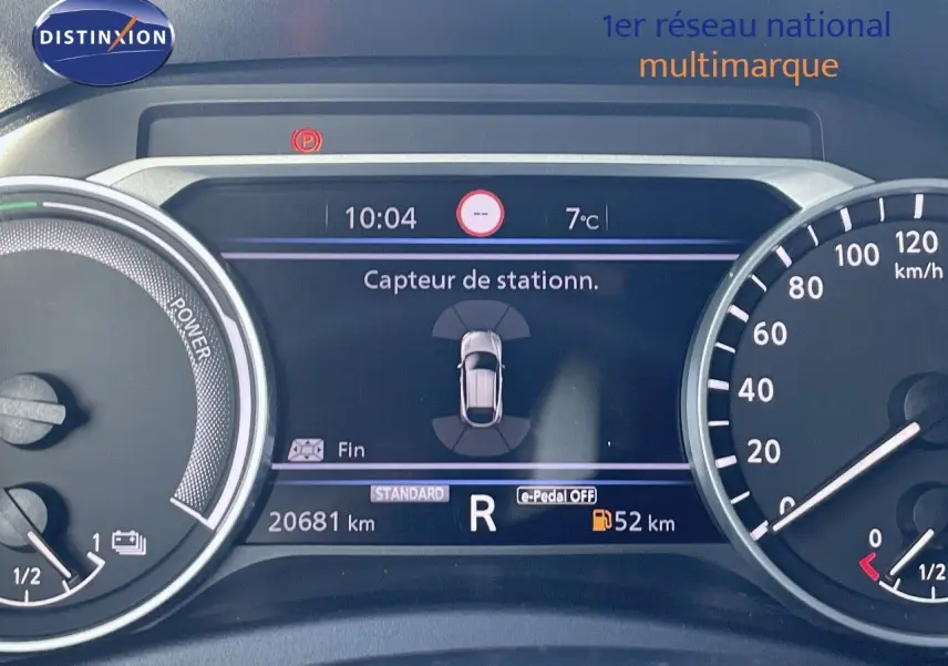 Tableau de bord du Nissan Juke gris squale métal 2024 montrant l'affichage du capteur de stationnement et le compteur kilométrique.