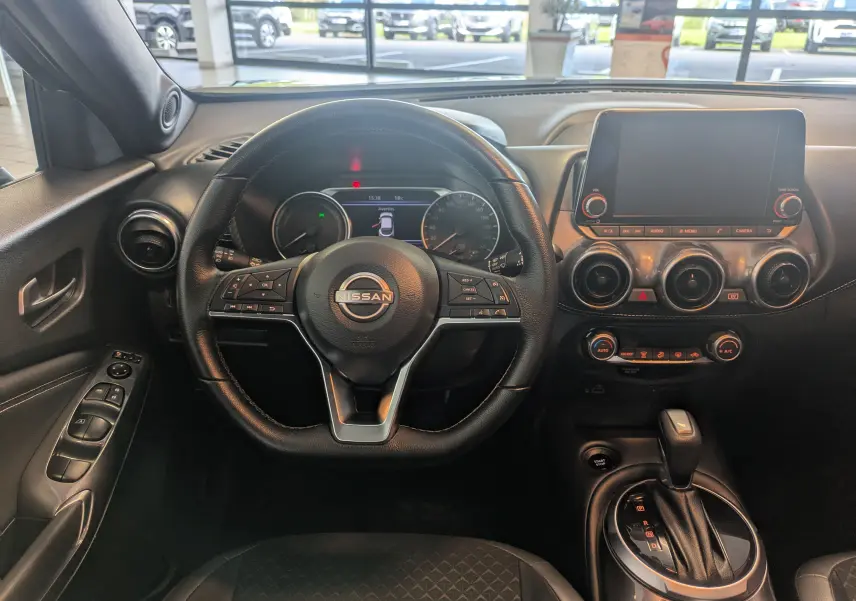 Vue intérieure du tableau de bord du Nissan Juke 2024, volant cuir noir et écran tactile central éteint.