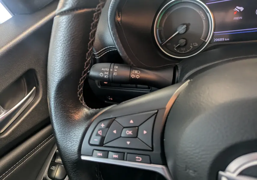 Gros plan sur le volant et les commandes à gauche du tableau de bord d'un Nissan Juke 2024 gris squale métal hybride.