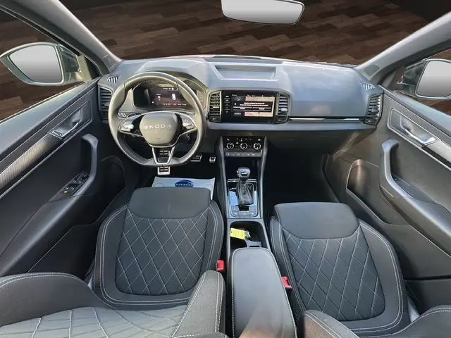 Vue intérieure avant du Skoda Karoq 2025 gris graphite, avec tableau de bord digital, volant multifonction et sièges sport noirs.