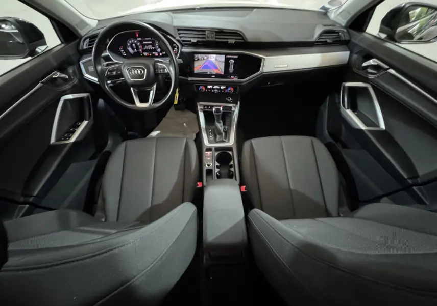 Intérieur noir de l'Audi Q3 2022, vue avant du poste de conduite avec écran tactile et volant multifonctions cuir.