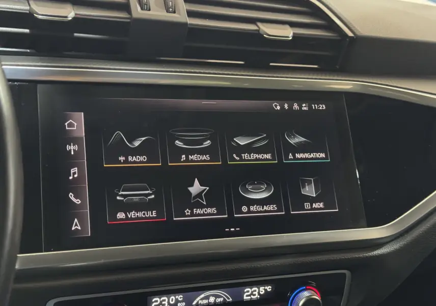 Écran tactile central de l'Audi Q3 2022 affichant les menus radio, médias, téléphone et navigation, vue de face rapprochée.