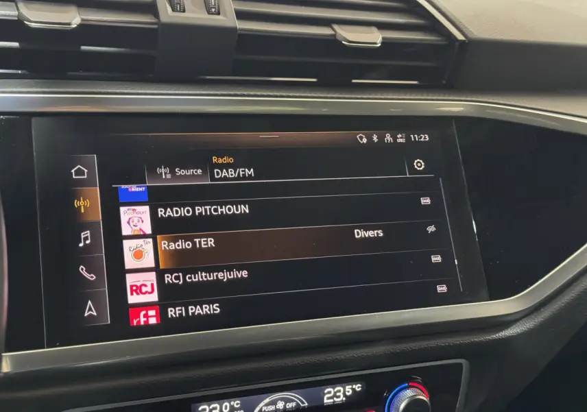 Écran tactile central affichant les stations radio DAB/FM dans l'habitacle noir de l'Audi Q3 35 TFSI 2022.
