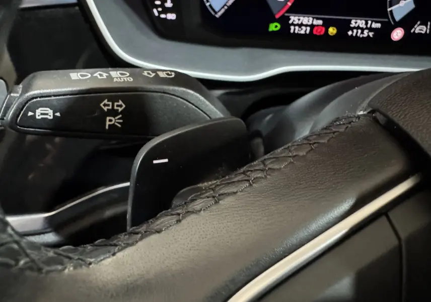 Gros plan sur le volant cuir noir et la commande de clignotants du tableau de bord numérique de l'Audi Q3 35 TFSI 2022.