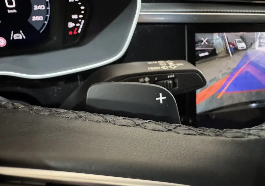 Détail du levier de vitesse au volant et écran de caméra de recul dans l'Audi Q3 noir 2022, vue intérieure rapprochée.