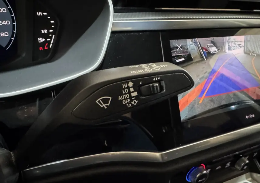 Gros plan sur la commande d’essuie-glace et l’écran de caméra de recul dans l’habitacle noir de l’Audi Q3 2022.