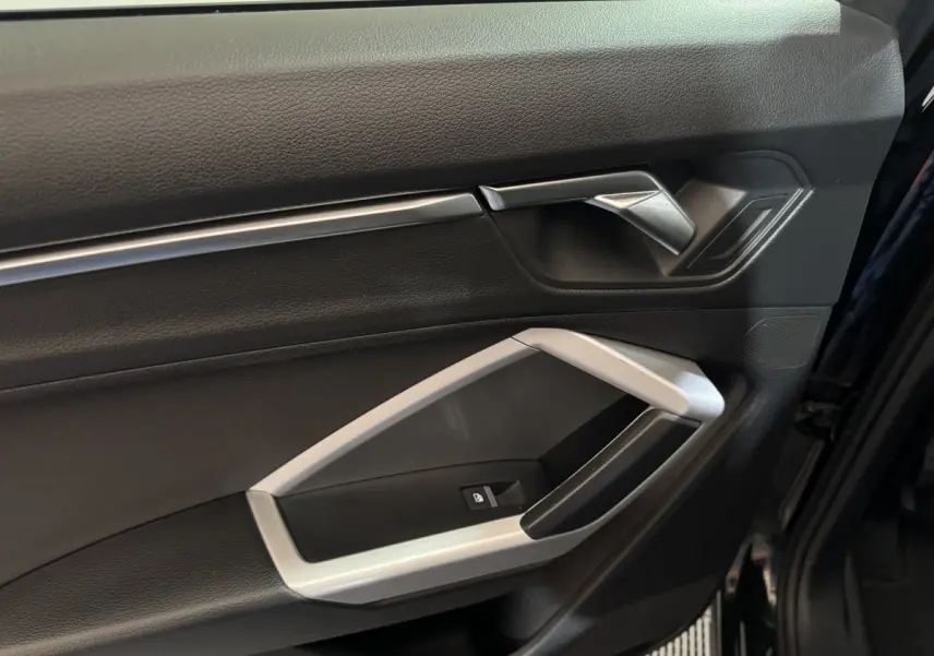 Gros plan sur la porte côté conducteur noire de l'Audi Q3 35 TFSI 2022 avec poignée argentée et bouton de verrouillage.