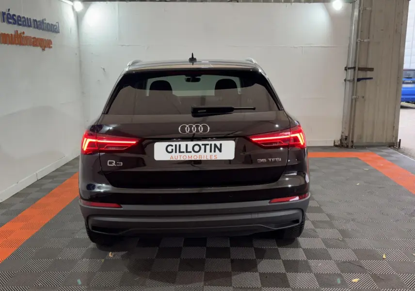 Vue arrière d'un Audi Q3 noir 35 TFSI avec feux LED allumés dans un garage fermé.