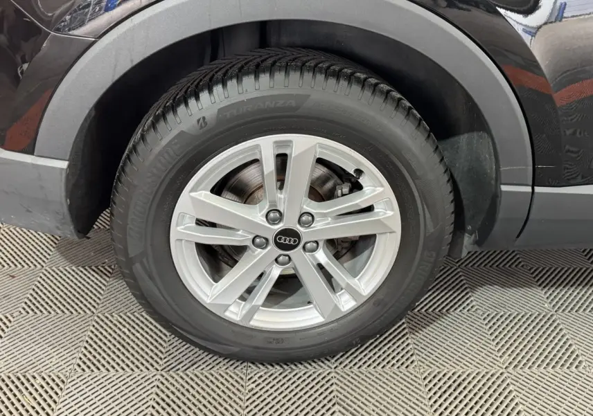 Gros plan sur la roue arrière droite d’un Audi Q3 noir 2022, mettant en valeur la jante argentée et le pneu Bridgestone.