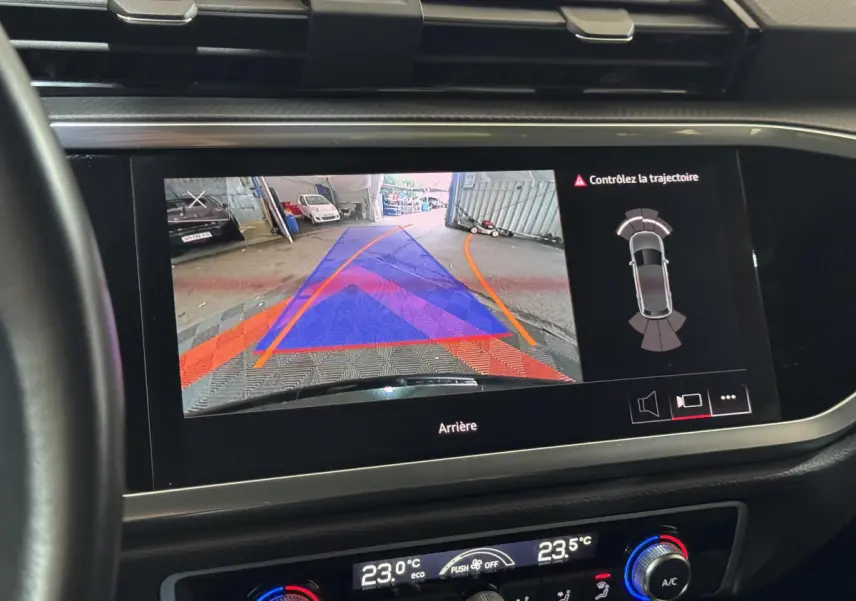 Écran tactile intérieur montrant la caméra de recul et l’aide au stationnement du tableau de bord d’un Audi Q3 noir.