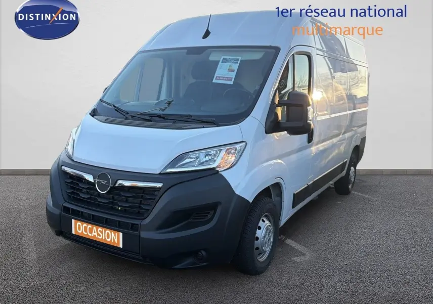 Fourgon Opel Movano blanc icy vu en 3/4 avant droit avec calandre noire et plaque "OCCASION" orange.