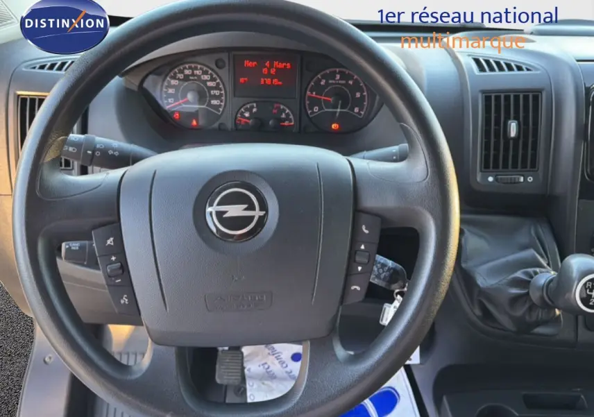 Vue rapprochée du volant noir de l'Opel Movano Fourgon 2023 avec tableau de bord et levier de vitesses manuel visible.