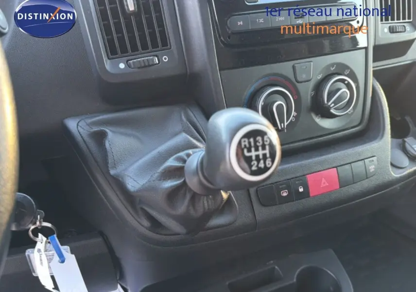 Gros plan sur la boîte manuelle et la console centrale noire de l'Opel Movano Fourgon blanc, avec commandes de climatisation visibles.