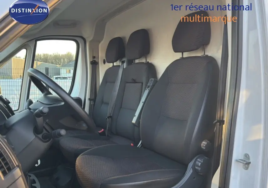Vue intérieure côté conducteur montrant les sièges noirs du fourgon Opel Movano blanc, version L2H2 2023.