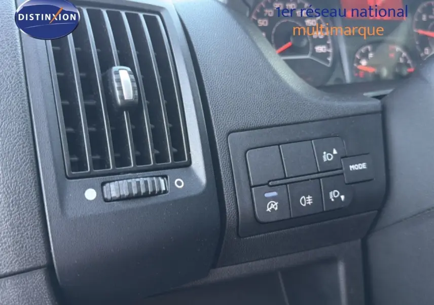 Détail intérieur montrant la grille d'aération et les commandes d'éclairage du tableau de bord d'un Opel Movano blanc.