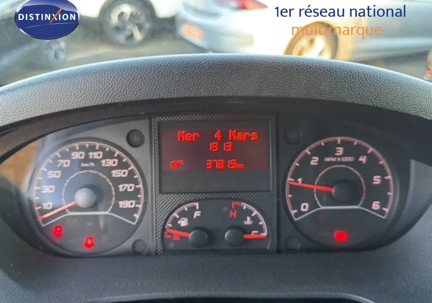 Vue rapprochée du tableau de bord du fourgon Opel Movano blanc, affichant le compteur et l'ordinateur de bord rouge.