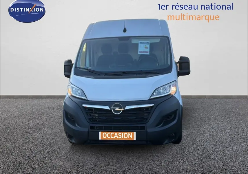 Vue avant d’un Opel Movano Fourgon blanc Icy 2023 avec calandre noire et plaque orange « Occasion » sur fond neutre.