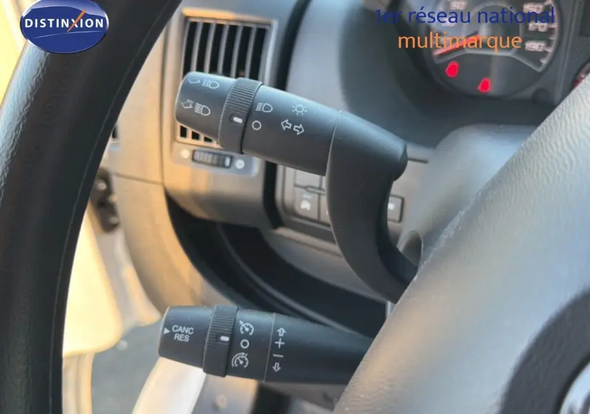 Gros plan sur les commandes de clignotants et régulateur de vitesse derrière le volant d'un Opel Movano Fourgon blanc 2023.