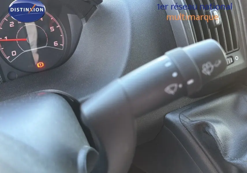 Gros plan sur la commande d’essuie-glace à gauche du volant dans l’habitacle noir d’un Opel Movano Fourgon blanc.