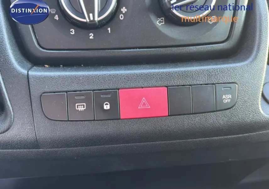 Gros plan sur la console centrale noire de l'Opel Movano Fourgon 2023, avec boutons de sécurité et climatisation.