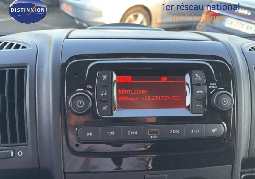 Vue rapprochée du tableau de bord noir de l’Opel Movano Fourgon 2023, avec l’écran radio affichant une station DAB+ rouge.