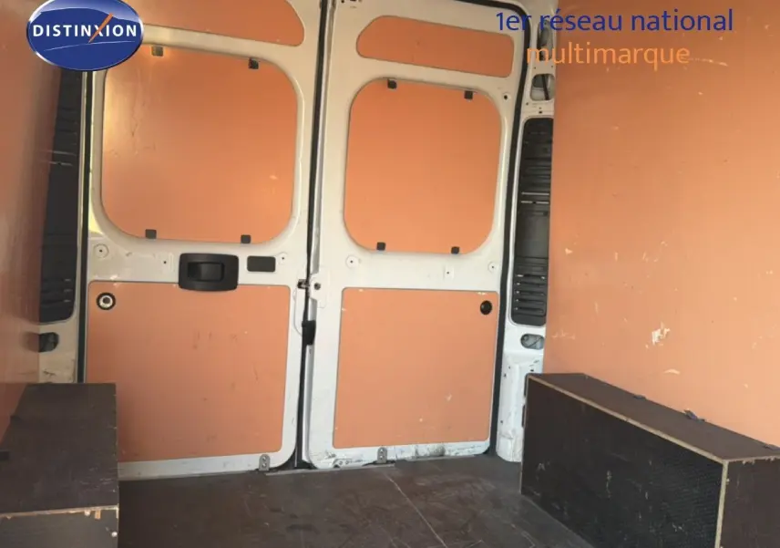 Vue intérieure arrière du fourgon blanc Opel Movano L2H2 2023, montrant les portes ouvertes et le plancher avec protections latérales.