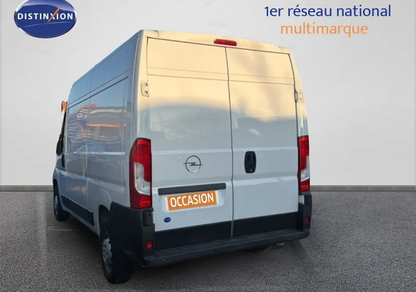 Vue 3/4 arrière gauche d’un Opel Movano Fourgon blanc icy, avec portes arrière fermées et logo Opel visible.