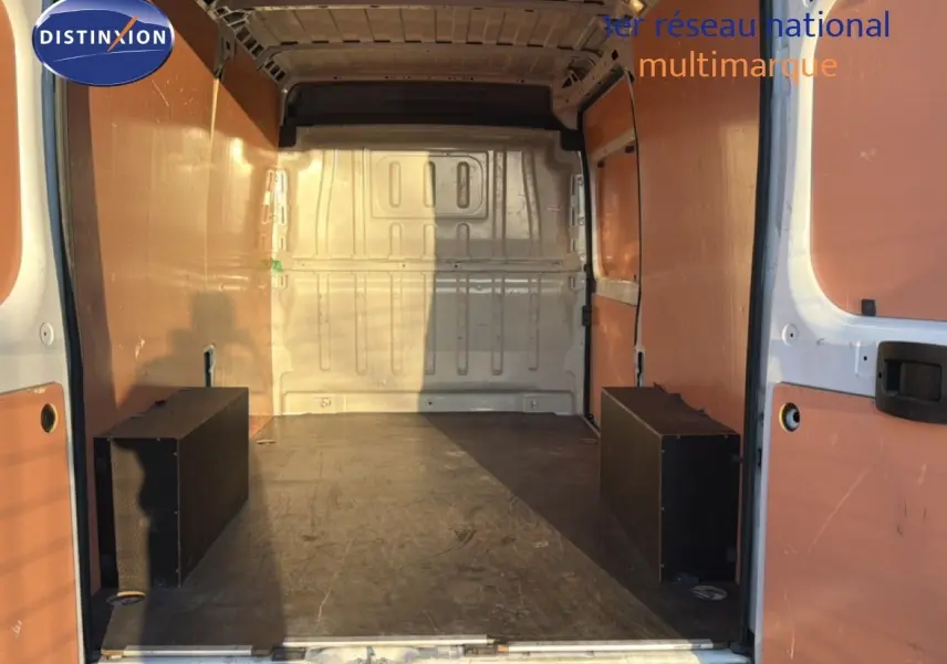 Vue intérieure arrière du fourgon Opel Movano blanc icy, montrant l'espace de chargement avec parois en bois et plancher noir.