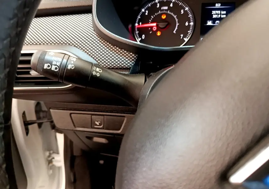 Vue rapprochée du combiné d'instruments et du commodo gauche du tableau de bord d'une Dacia Sandero blanche 2022.