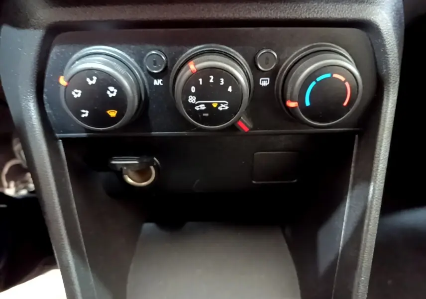 Gros plan sur les commandes de climatisation manuelle de la Dacia Sandero Confort TCe 90, tableau de bord noir.