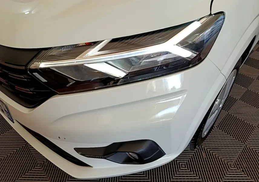 Gros plan sur l'avant droit blanc du Dacia Sandero 2022, mettant en valeur ses phares LED et antibrouillards.