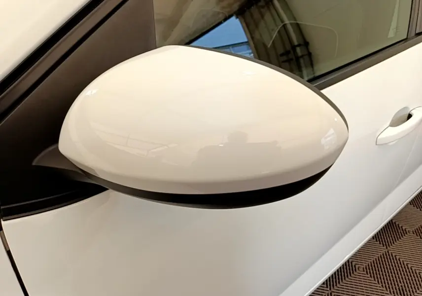 Gros plan sur le rétroviseur côté gauche blanc d'une Dacia Sandero Confort TCe 90 2022, avec porte et poignée visibles.