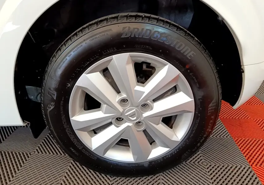 Gros plan sur la roue avant droite blanche d'une Dacia Sandero 2022 avec jante argentée et pneu Bridgestone.