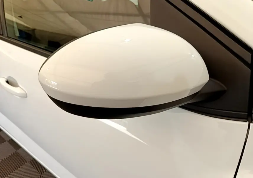 Gros plan sur le rétroviseur côté gauche blanc d'une Dacia Sandero Confort TCe 90 2022, avec porte et poignée visibles.