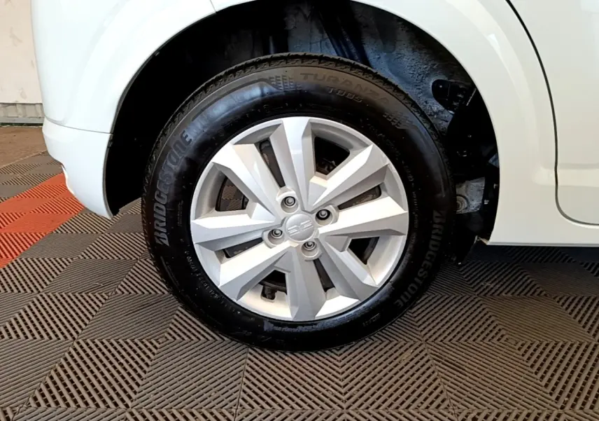 Gros plan sur la roue avant droite d'une Dacia Sandero blanche, mettant en valeur la jante en alliage et le pneu Bridgestone.