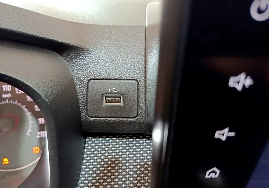 Gros plan sur la prise USB intégrée au tableau de bord noir de la Dacia Sandero blanche, côté conducteur.